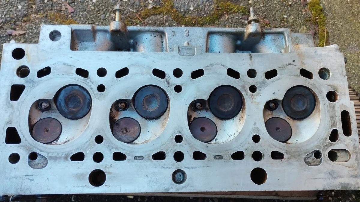 Combustion-chamber side of a used four-cylinder head with four pairs of valves and its gasket face visible